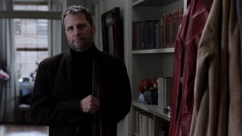 Movie still from “The Hours” (2002), directed by Stephen Daldry – A man standing in front of a bookshelf holding a book; Medium shot, Over the shoulder angle