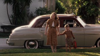 Movie still from “The Hours” (2002), directed by Stephen Daldry – A woman and a boy holding hands in front of an antique car; Wide shot, Low angle