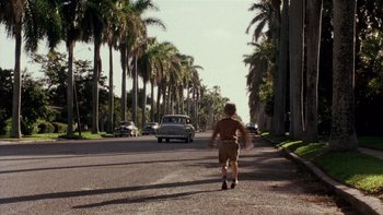 Movie still from “The Hours” (2002), directed by Stephen Daldry – A young boy walking down a street with palm trees in the background; Wide shot, High angle