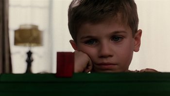 Movie still from “The Hours” (2002), directed by Stephen Daldry – A young boy sitting in front of a red object; Close Up shot, Over the shoulder angle