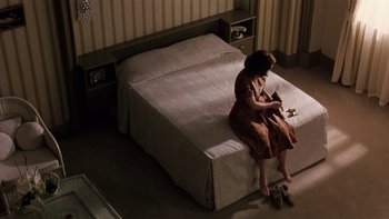 Movie still from “The Hours” (2002), directed by Stephen Daldry – A woman sitting on top of a bed in a bedroom; Wide shot, High angle