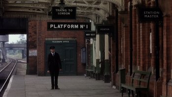 Movie still from “The Hours” (2002), directed by Stephen Daldry – A man standing in front of a train station; Wide shot, Low angle