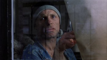 Movie still from “The Hours” (2002), directed by Stephen Daldry – A man in a blue shirt and a gray hat is holding a knife; Close Up shot, Low angle