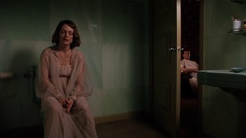 Movie still from “The Hours” (2002), directed by Stephen Daldry – A woman sitting in front of a door while a man sits on the other side of the door; Medium shot, High angle