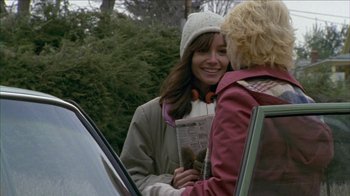 Movie still from “The House of the Devil” (2009), directed by Ti West – Two women standing next to each other in front of a parked car; Medium shot, Over the shoulder angle