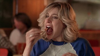 Movie still from “The House of the Devil” (2009), directed by Ti West – A woman is eating a piece of food; Close Up shot, Over the shoulder angle