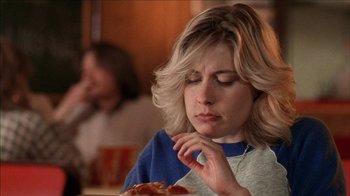 Movie still from “The House of the Devil” (2009), directed by Ti West – A woman sitting at a table with a piece of pizza; Close Up shot, Over the shoulder angle