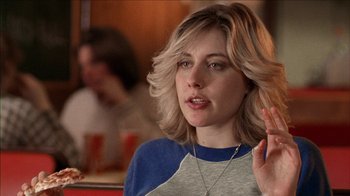 Movie still from “The House of the Devil” (2009), directed by Ti West – A woman with blonde hair is sitting at a table; Close Up shot, Over the shoulder angle