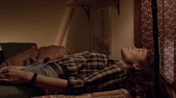 Movie still from “The House of the Devil” (2009), directed by Ti West – A person laying on a bed in a room; Medium shot, High angle