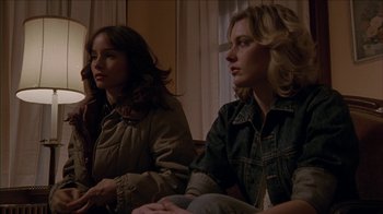 Movie still from “The House of the Devil” (2009), directed by Ti West – Two women sitting on a couch looking at something on the wall; Medium shot, Low angle