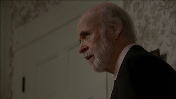 Movie still from “The House of the Devil” (2009), directed by Ti West – An older man in a suit and tie; Close Up shot, Over the shoulder angle
