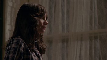 Movie still from “The House of the Devil” (2009), directed by Ti West – A woman in a plaid shirt looking out a window; Close Up shot, Over the shoulder angle