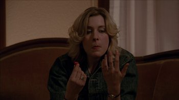 Movie still from “The House of the Devil” (2009), directed by Ti West – A woman sitting in front of a wall with her fingers crossed; Close Up shot, High angle