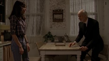 Movie still from “The House of the Devil” (2009), directed by Ti West – A man and a woman are standing in front of a dining room table; Medium shot, Over the shoulder angle