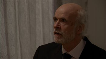 Movie still from “The House of the Devil” (2009), directed by Ti West – An older man in a black suit and white shirt; Close Up shot, Over the shoulder angle