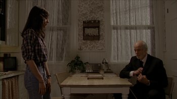 Movie still from “The House of the Devil” (2009), directed by Ti West – A man and a woman are sitting at a dining room table; Medium shot, Over the shoulder angle
