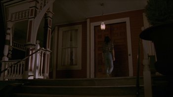Movie still from “The House of the Devil” (2009), directed by Ti West – A person walking down the stairs of a house; Wide shot, Low angle
