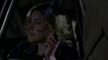 Movie still from “The House of the Devil” (2009), directed by Ti West – A woman sitting in the back seat of a car while holding a cell phone to her ear; Close Up shot, Low angle