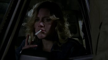 Movie still from “The House of the Devil” (2009), directed by Ti West – A woman sitting in a car with a cigarette in her mouth; Close Up shot, Over the shoulder angle