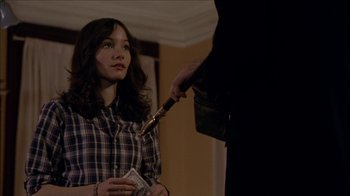 Movie still from “The House of the Devil” (2009), directed by Ti West – A woman is holding a knife and looking at a man; Medium shot, Over the shoulder angle