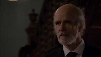 Movie still from “The House of the Devil” (2009), directed by Ti West – An older man in a black suit and white tie; Close Up shot, Low angle