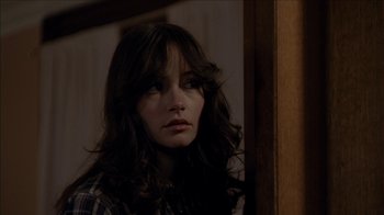 Movie still from “The House of the Devil” (2009), directed by Ti West – A woman with long brown hair looking at the camera; Close Up shot, Over the shoulder angle