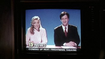 Movie still from “The House of the Devil” (2009), directed by Ti West – Two people sitting in front of a news desk; Medium shot, High angle