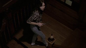 Movie still from “The House of the Devil” (2009), directed by Ti West – A woman holding a knife in her hand; Medium shot, High angle