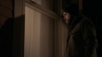 Movie still from “The House of the Devil” (2009), directed by Ti West – A man standing in front of a window looking outside; Close Up shot, Low angle
