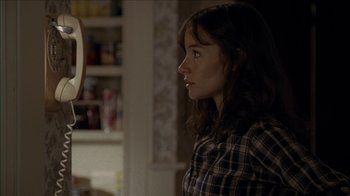 Movie still from “The House of the Devil” (2009), directed by Ti West – A young girl looking into a mirror in a room; Close Up shot, Over the shoulder angle