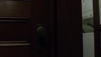 Movie still from “The House of the Devil” (2009), directed by Ti West – A door with a brass door knob and a wooden door; Extreme Close Up shot, High angle