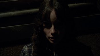 Movie still from “The House of the Devil” (2009), directed by Ti West – A woman with long dark hair sitting in a dark room; Close Up shot, High angle