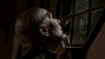 Movie still from “The House of the Devil” (2009), directed by Ti West – A man with a long white hair looking out of a window; Close Up shot, Low angle