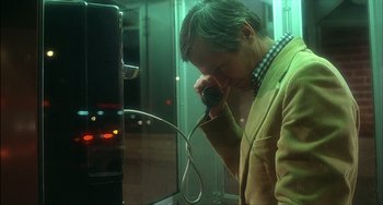 Movie still from “The Howling” (1981), directed by Joe Dante – A man in a yellow jacket is talking on a phone; Medium shot, Over the shoulder angle