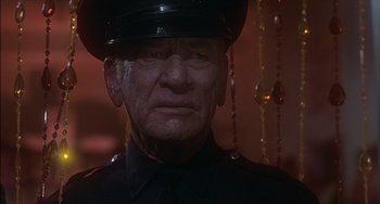 Movie still from “The Howling” (1981), directed by Joe Dante – An old man wearing a police uniform and wearing a hat; Close Up shot, Low angle