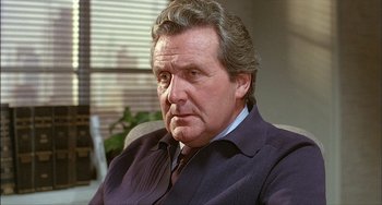 Movie still from “The Howling” (1981), directed by Joe Dante – An older man wearing a suit and a tie; Close Up shot, Low angle