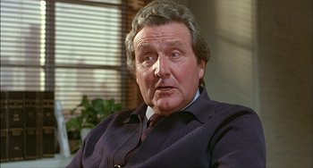 Movie still from “The Howling” (1981), directed by Joe Dante – An older man in a suit and tie looking at the camera; Close Up shot, Low angle