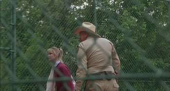 Movie still from “The Howling” (1981), directed by Joe Dante – A man and a woman are standing in front of a chain link fence; Medium shot, Over the shoulder angle
