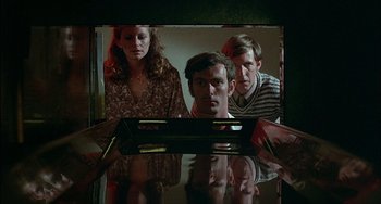 Movie still from “The Howling” (1981), directed by Joe Dante – Two men and a woman looking at a television screen; Medium shot, High angle
