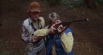 Movie still from “The Howling” (1981), directed by Joe Dante – A man and a woman holding a gun in the woods; Medium shot, High angle