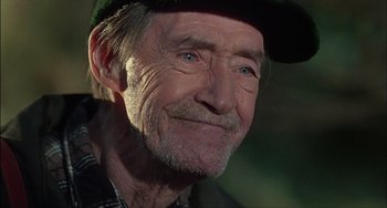 Movie still from “The Howling” (1981), directed by Joe Dante – An old man with a beard wearing a green hat; Close Up shot, Over the shoulder angle
