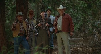 Movie still from “The Howling” (1981), directed by Joe Dante – A group of men standing next to each other in the woods; Medium shot, Low angle