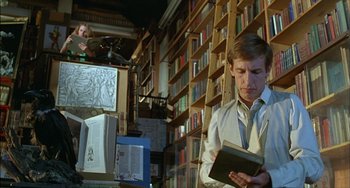 Movie still from “The Howling” (1981), directed by Joe Dante – A man is reading a book in a room full of bookshelves; Medium shot, Low angle