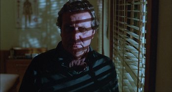 Movie still from “The Howling” (1981), directed by Joe Dante – A man in a striped shirt is standing in front of a window; Close Up shot, Low angle