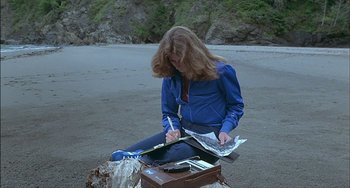 Movie still from “The Howling” (1981), directed by Joe Dante – A woman sitting on the ground writing on a piece of paper; Medium shot, High angle