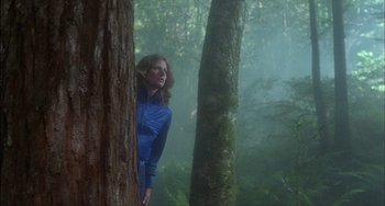 Movie still from “The Howling” (1981), directed by Joe Dante – A woman standing next to a tree in the woods; Wide shot, Low angle