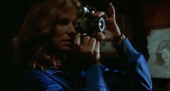 Movie still from “The Howling” (1981), directed by Joe Dante – A woman taking a picture with a camera; Close Up shot, Over the shoulder angle