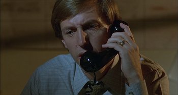 Movie still from “The Howling” (1981), directed by Joe Dante – A man holding a phone up to his ear; Close Up shot, Low angle