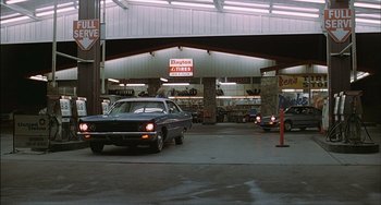 Movie still from “The Howling” (1981), directed by Joe Dante – A car parked in front of a building with a lot of cars parked in front of it; Wide shot, Low angle