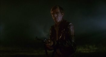 Movie still from “The Howling” (1981), directed by Joe Dante – A man in a leather jacket holding a gun in his hands; Medium shot, Low angle